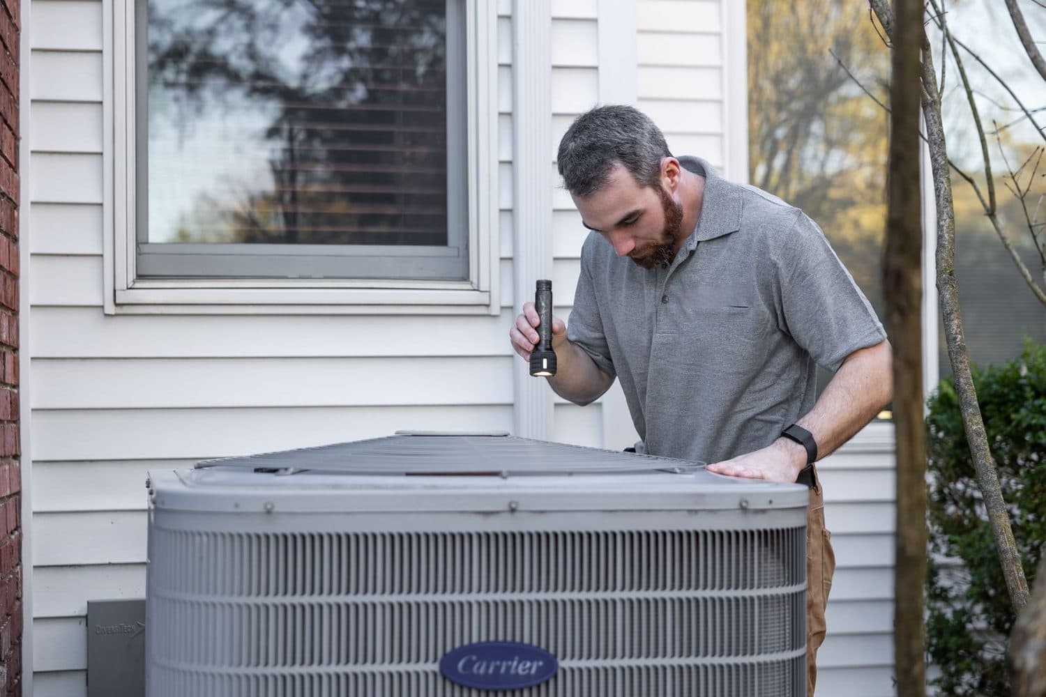 HVAC technician servicing an outdoor air conditioner condenser at a home