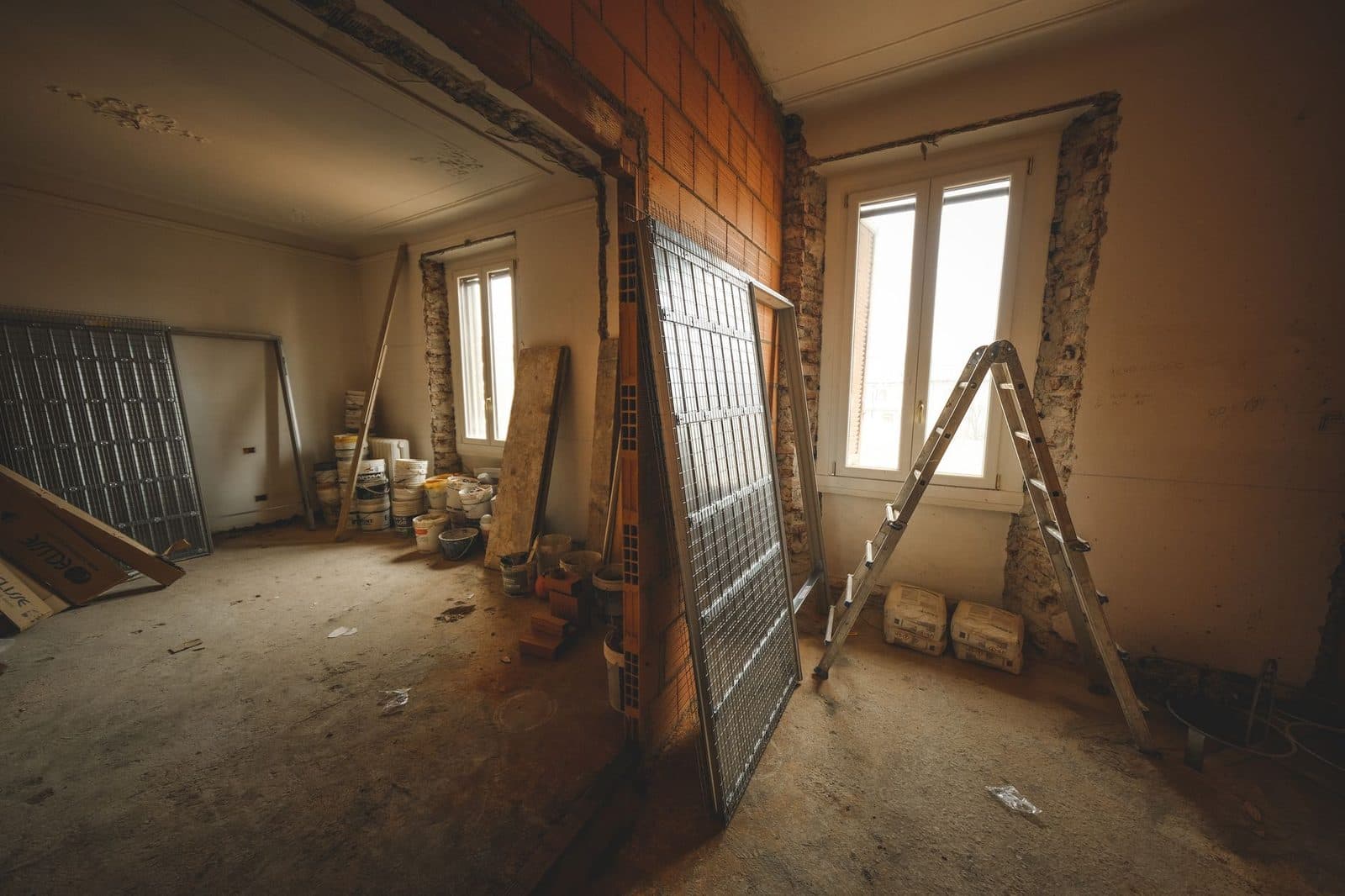 Room stripped back to masonry during interior repair, with materials and a ladder staged